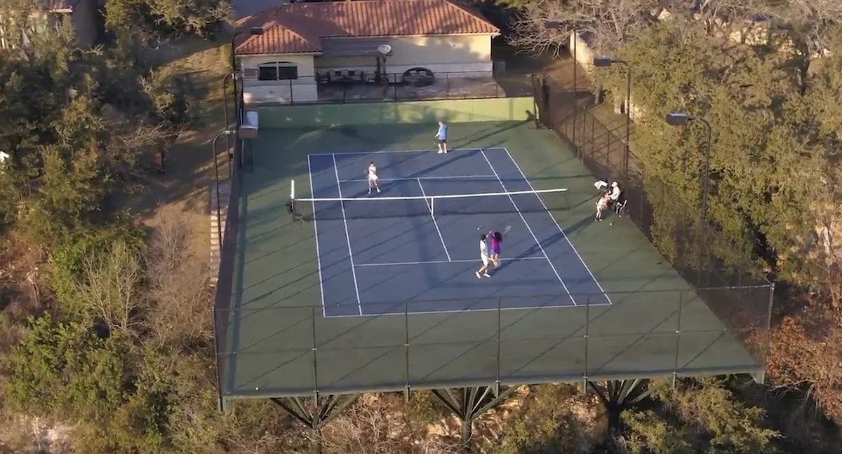 Vista aérea de una pista de tenis elevada por encima de las copas de los árboles
