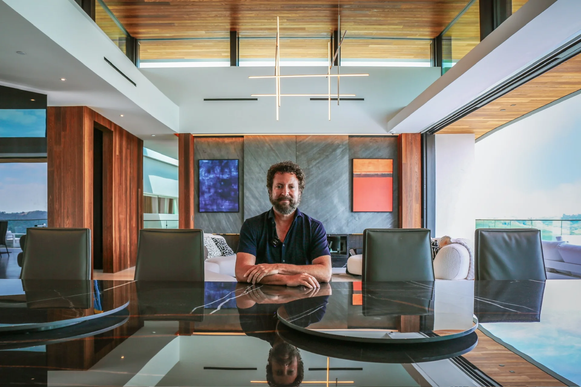 Winn Wittman seated at dining table beneath sculptural lighting