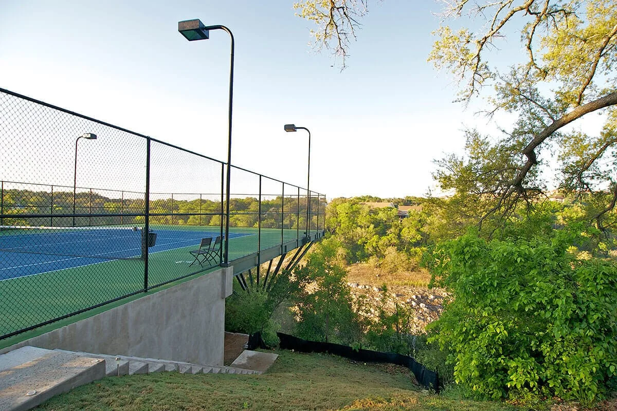 Pista de tenis elevada, suspendida al borde de un barranco arbolado